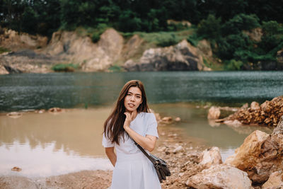 Young woman standing against lake