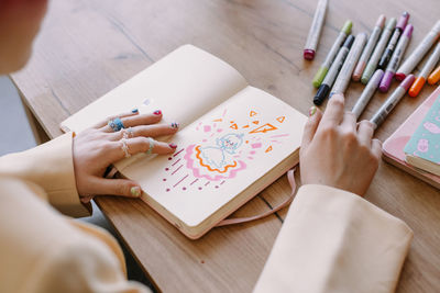 Woman drawing in diary at table