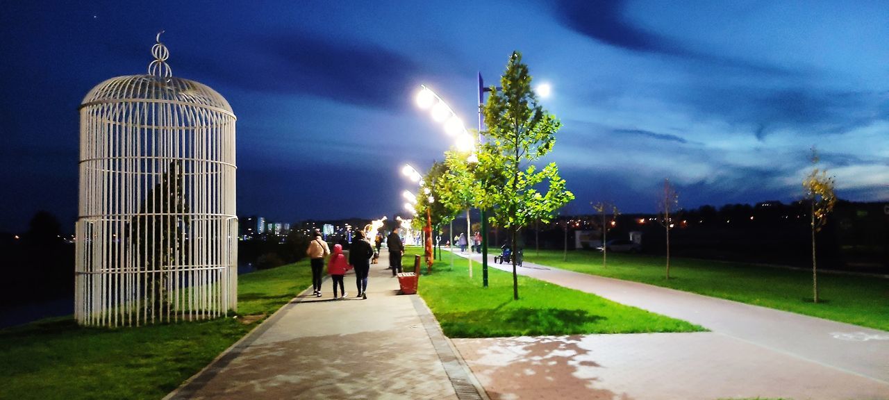 architecture, sky, group of people, night, nature, plant, built structure, building exterior, cloud, landmark, grass, city, adult, travel destinations, men, tree, outdoors, footpath, illuminated, building, women