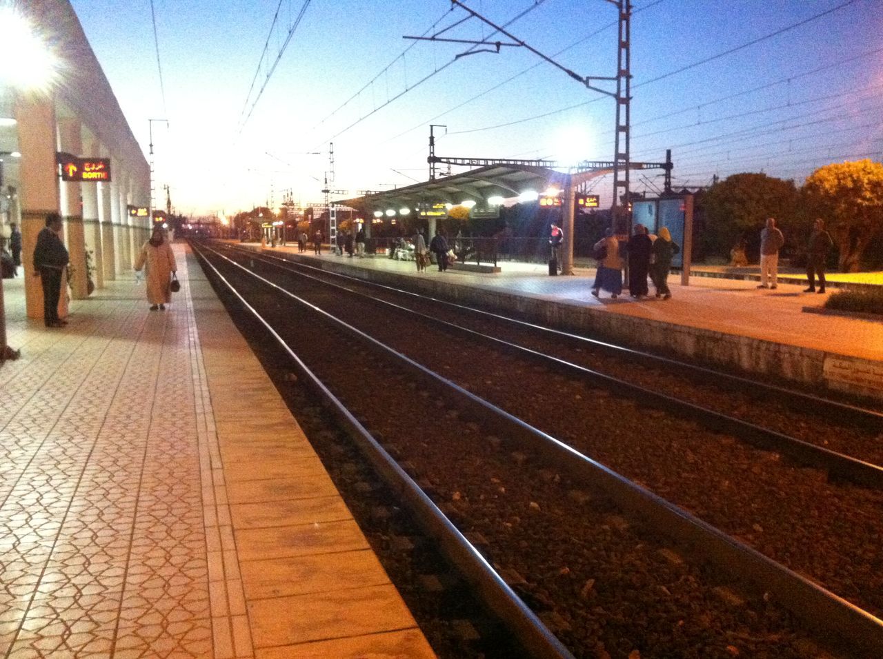 railroad track, transportation, building exterior, city, railroad station platform, built structure, rail transportation, railroad station, public transportation, architecture, city life, the way forward, diminishing perspective, person, sky, travel, incidental people, men, power line