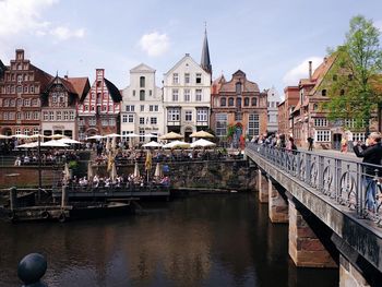 Group of people on bridge over river against buildings in city