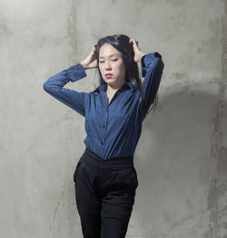 Beautiful young woman standing against wall