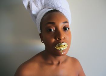 Portrait of shirtless woman with golden lipstick against wall