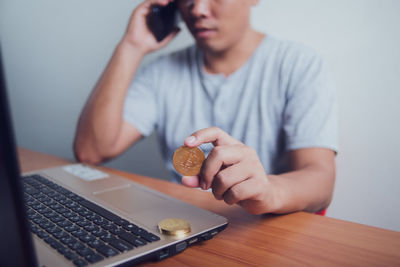 Midsection of man holding smart phone on table