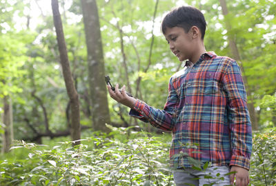 Man using mobile phone while standing on tree