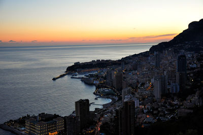 Aerial view of city at waterfront during sunset