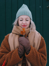Young smiling blonde woman having fun on a christmas market and eating rooster-shaped lollipop
