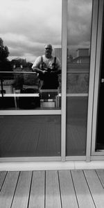 Reflection of man sitting on glass window