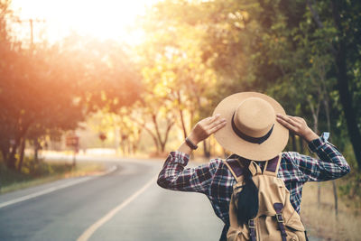 Rear view of woman wearing hat standing on road