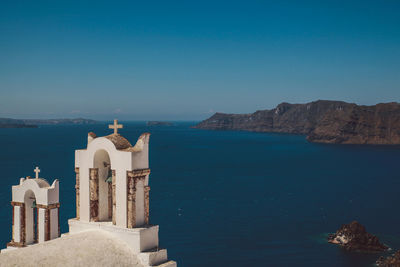 Church by blue sea against clear sky on sunny day