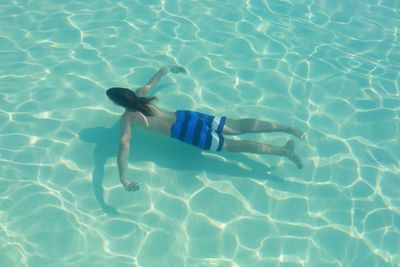 Rear view of young man swimming in pool