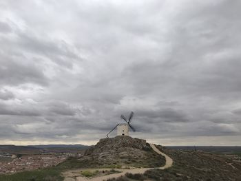 Rear view of man standing on field against cloudy sky