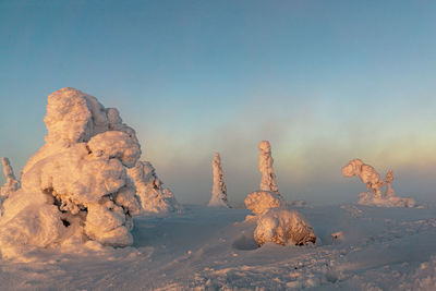 Rock formation on snow against sky