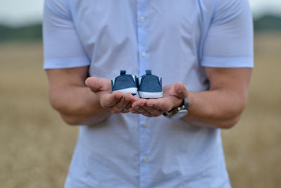 Father's hand holding blue baby shoes