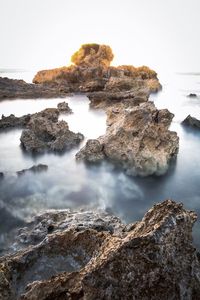 Scenic view of rocks in sea against sky