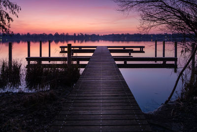 Pier over lake against sky during sunset