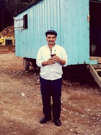 Full length of man holding mobile phone standing outdoors