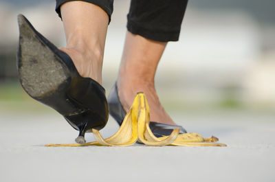 Low section of woman walking by banana peel on footpath