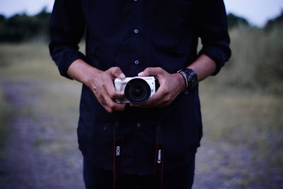 Midsection of man holding camera