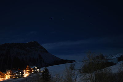 Illuminated houses on mountain against sky