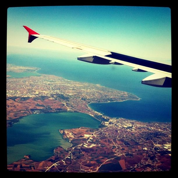 flying, airplane, aircraft wing, air vehicle, aerial view, transportation, mode of transport, mid-air, part of, cropped, blue, sky, travel, journey, airplane wing, sea, scenics, landscape, on the move, cityscape