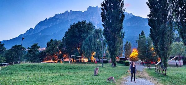 People on field against trees and mountains