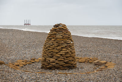 Stack of stones on beach against sky