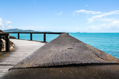 Rear view of pier leading towards sea against sky