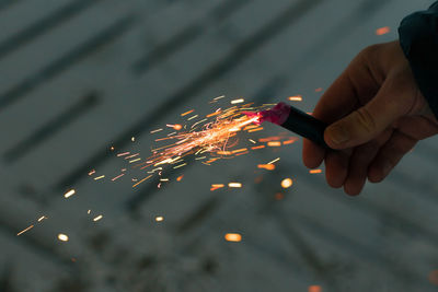 Cropped hand holding sparkler at night