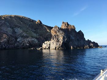 Rock formations by sea against blue sky