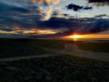 Scenic view of sea against dramatic sky during sunset