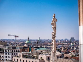 Statue in city against clear blue sky