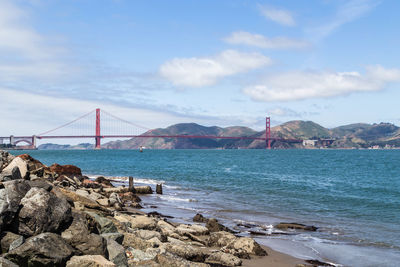 Suspension bridge over sea against sky