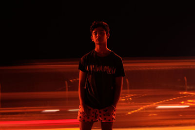 Full length of young man standing against light trails at night