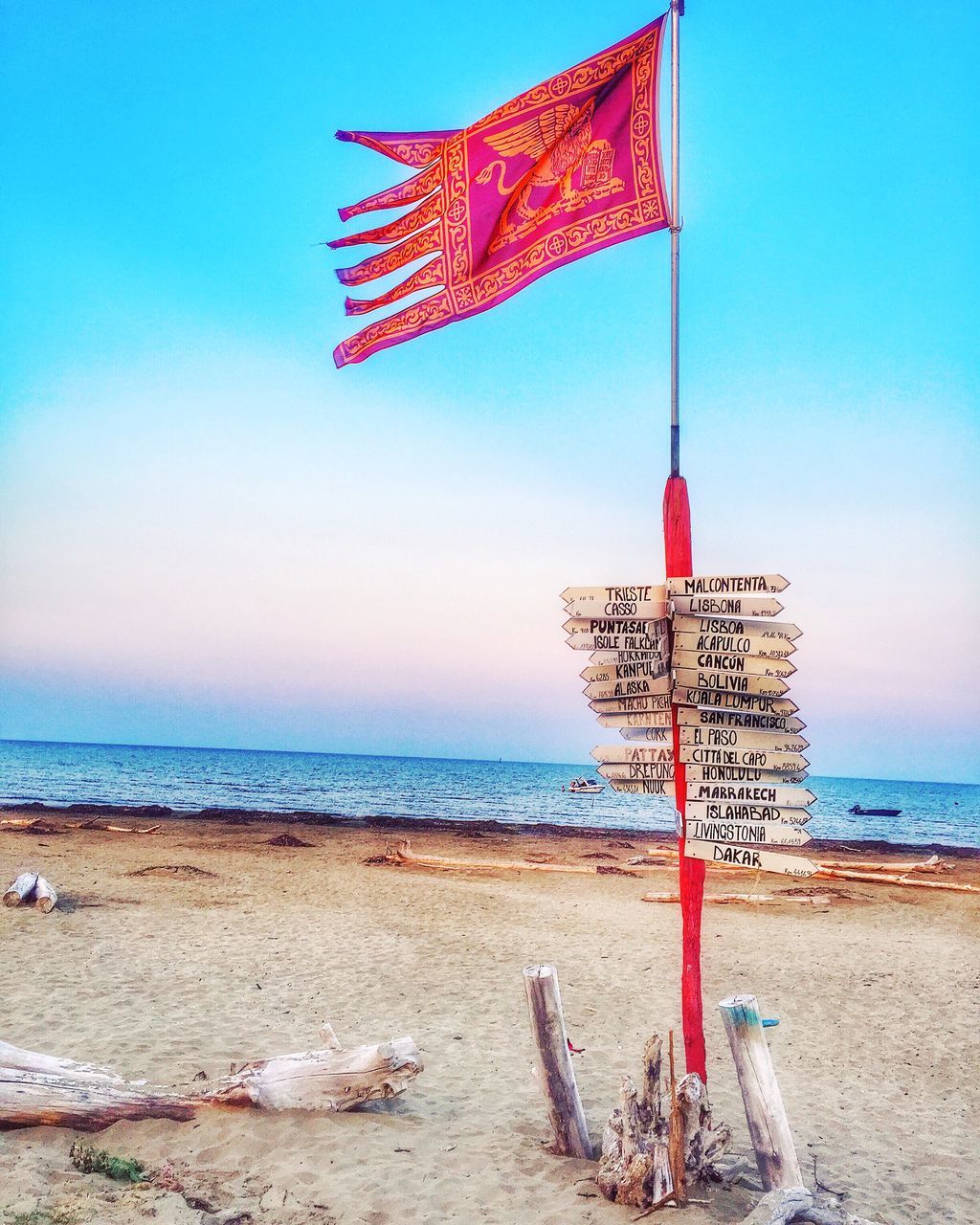 beach, sea, horizon over water, sand, shore, flag, water, clear sky, sky, tranquility, blue, scenics, tranquil scene, nature, beach umbrella, identity, beauty in nature, sunlight, patriotism, national flag