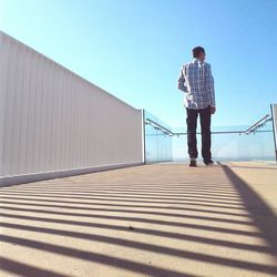 Full length of man standing on walkway against clear sky