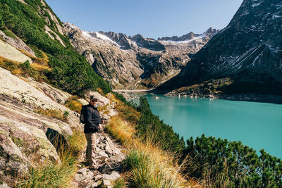 Man looking at lake by mountain against sky