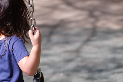 Close-up of girl holding chain at playground