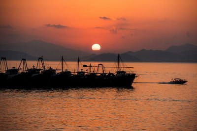 Silhouette sailboats in sea against sky during sunset