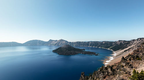 Panoramic view of sea and mountains against clear blue sky