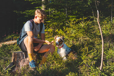 Candid portrait of a master feeding her australian shepherd dog on a walk in the woods