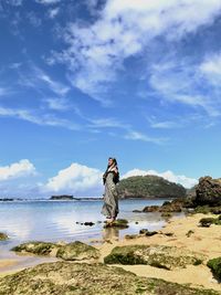 Woman standing at beach against sky