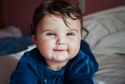 Portrait of cute baby girl on bed at home