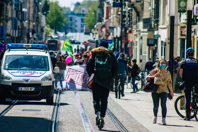 Rear view of people walking on city street