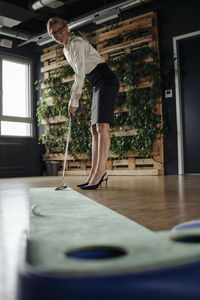 Businesswoman playing golf in office