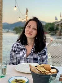 A girl in seaside restaurant. sunset over mountains on a background wall