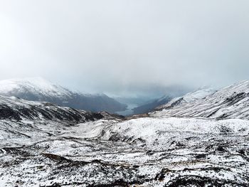 Scenic view of snow covered field against cloudy sky