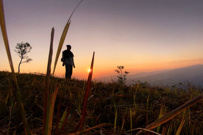 Man standing on field against sky during sunset