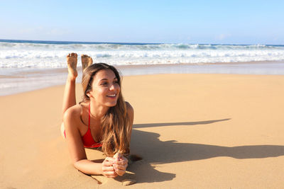 Happy young woman at beach against sky