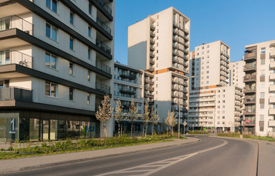 Road by buildings against sky in city